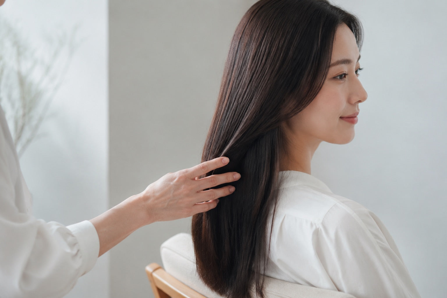 長い黒髪を整える日本人女性の秋のヘアケアイメージ